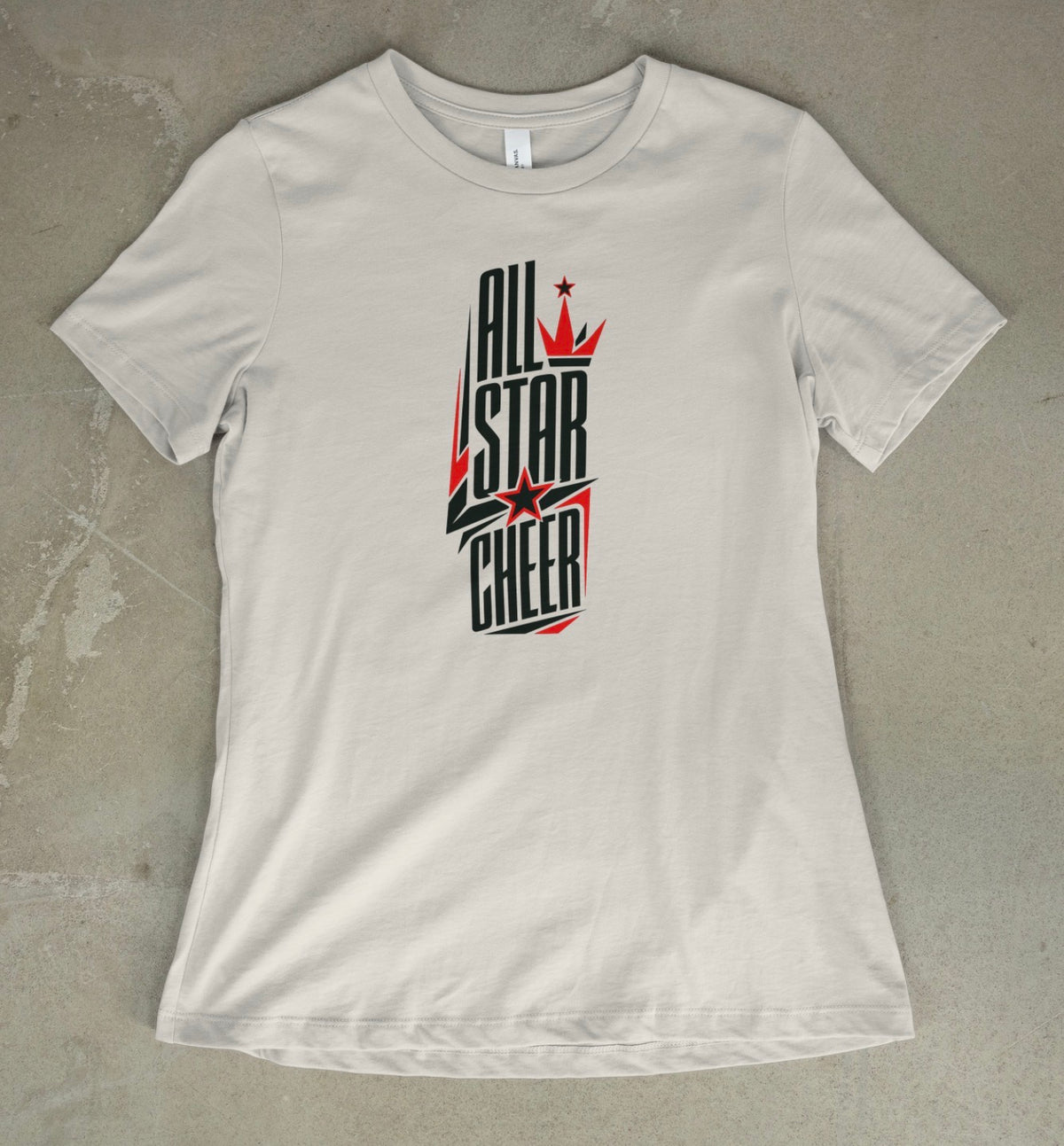 A vintage white short-sleeve t-shirt with a black and white 'All Star Cheer' graphic on the front, laid flat on a textured gray concrete surface.