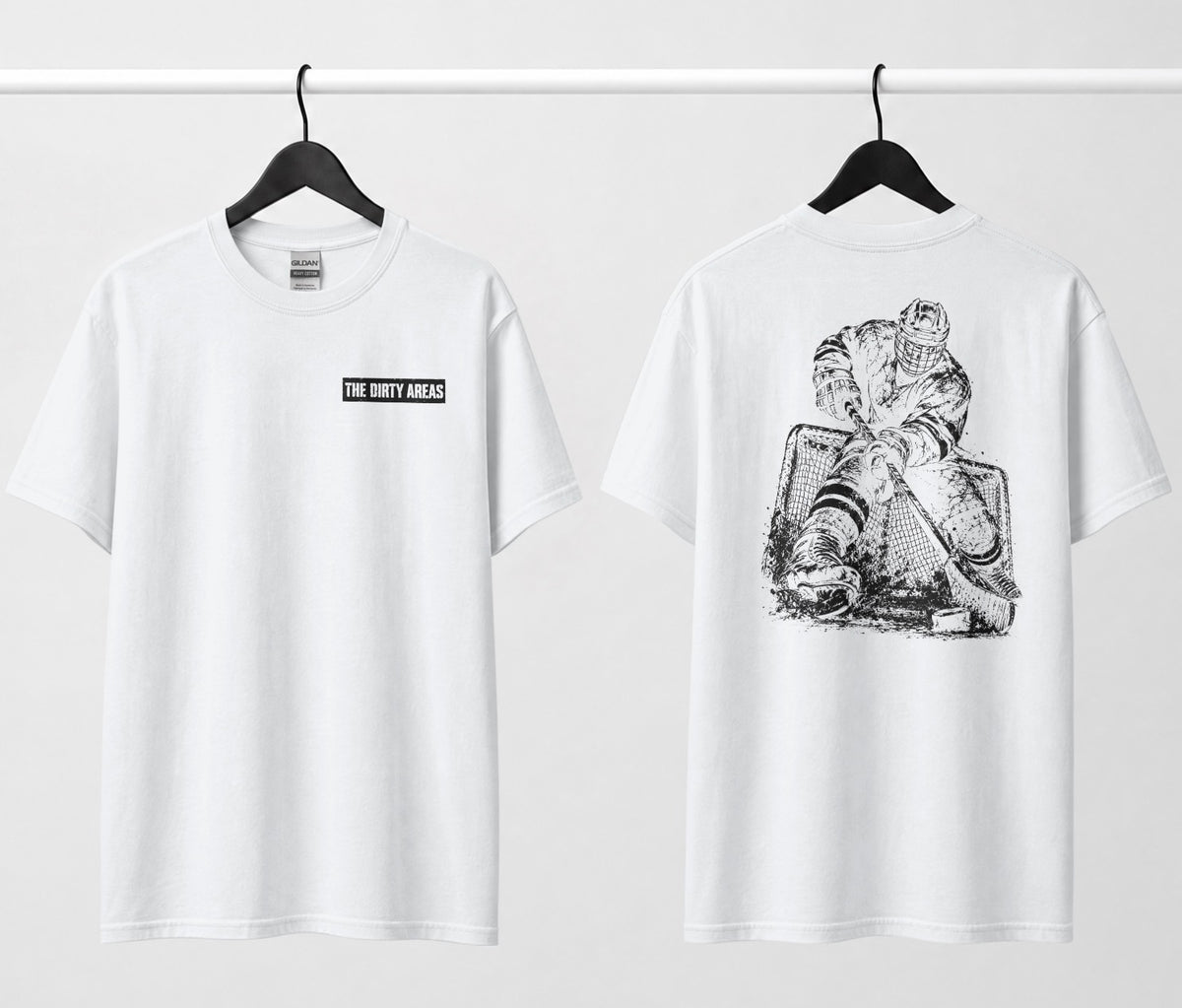 Front and back of a white t-shirt hanging side by side: the front has a small 'The Dirty Areas' label on the chest, and the back has a large black hockey player battling in front of the net.