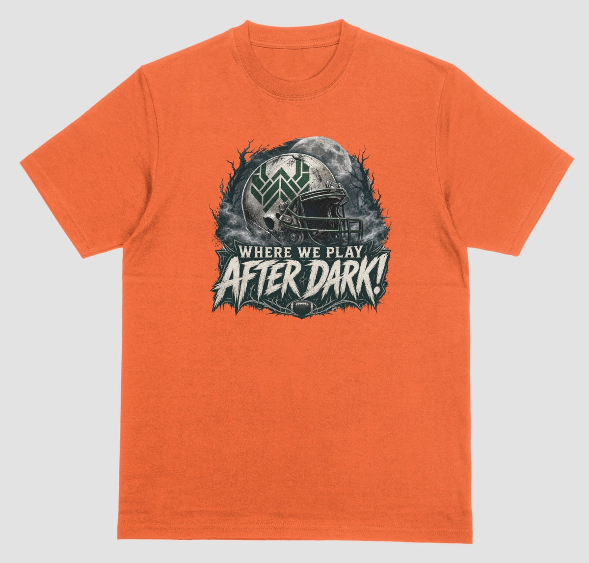 An orange t-shirt with a spooky football graphic reading 'Where We Play After Dark!' showing a weathered white helmet with a green 'W' logo in front of a full moon.