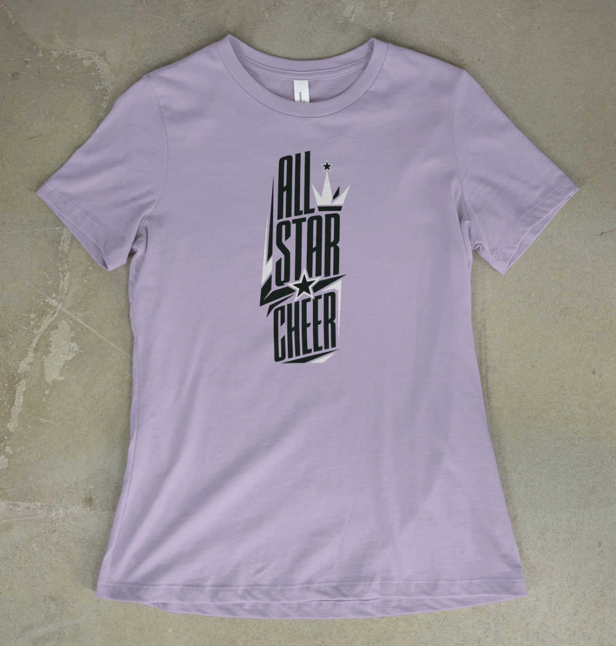 A light violet short-sleeve t-shirt with a black and white 'All Star Cheer' graphic on the front, laid flat on a textured gray concrete surface.