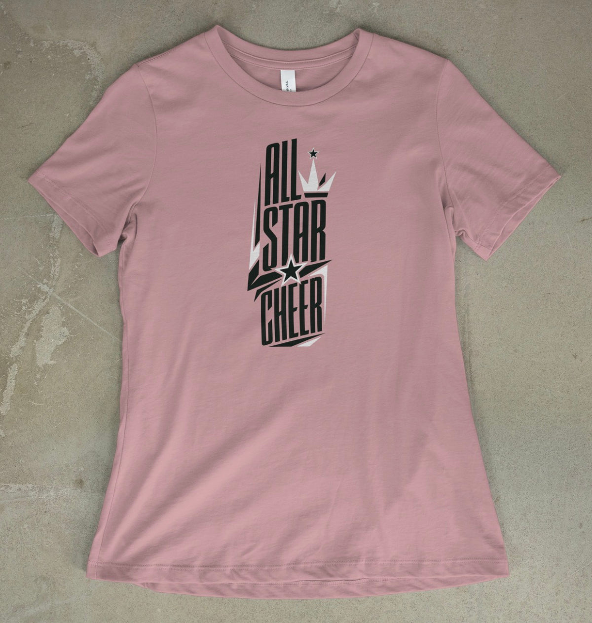 A pink gravel short-sleeve t-shirt with a black and white 'All Star Cheer' graphic on the front, laid flat on a textured gray concrete surface.