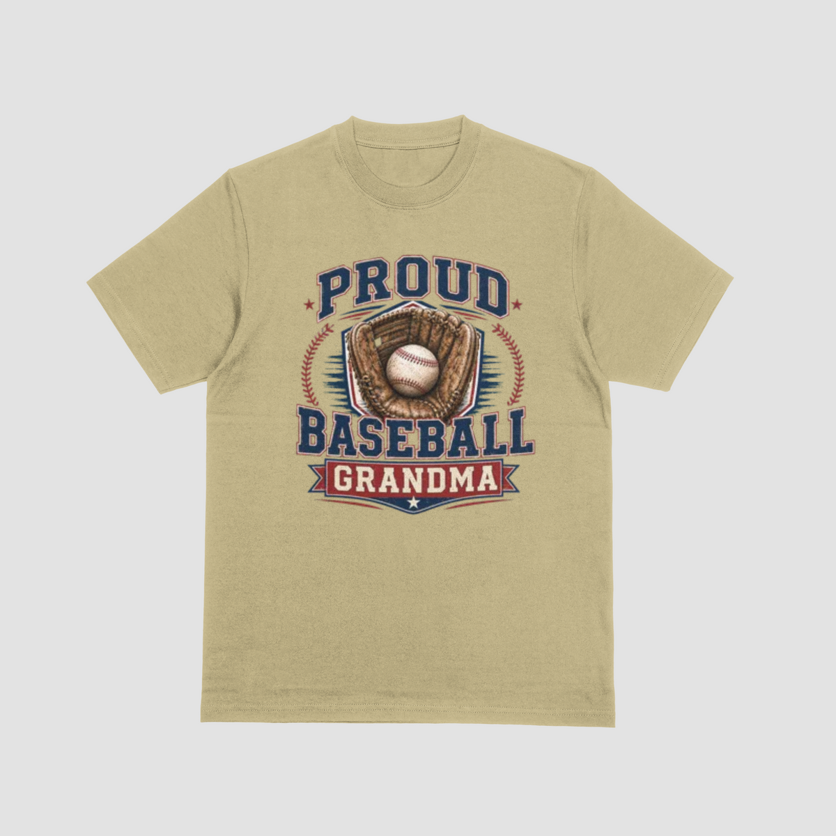 A sand color short-sleeve crewneck t-shirt with a vintage-style baseball graphic on the front. The graphic features the text 'PROUD BASEBALL GRANDMA' in navy blue and red, surrounding an illustration of a baseball in a brown glove.