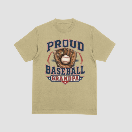 A sand color short-sleeve crewneck t-shirt featuring a vintage-style baseball graphic on the front. The graphic displays the text 'PROUD BASEBALL GRANDPA' in navy blue and red, surrounding an illustration of a baseball in a brown glove.