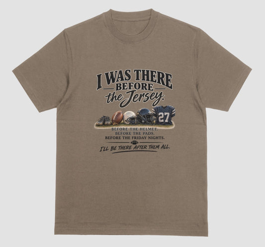 A brown savana short-sleeve t-shirt with a vintage-style football graphic on the chest. The graphic features footballs and a helmet and a jersey with the number 27, accompanied by the text 'I WAS THERE BEFORE the Jersey.