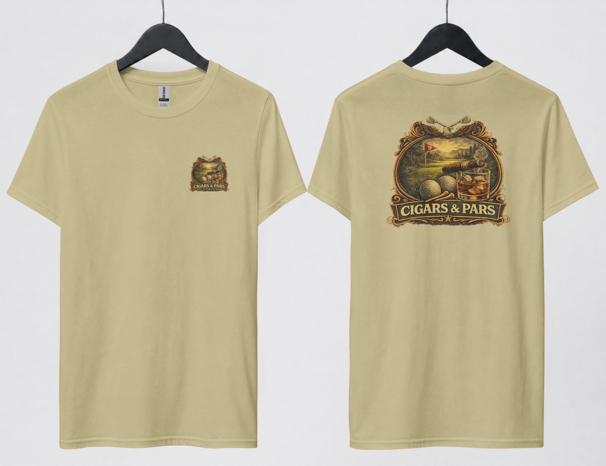 A sand color t-shirt, front and back views on hangers. Front features a small crest-style graphic on the left chest with a golf course scene, crossed clubs, golf balls, and a cigar, framed above a banner reading 'Cigars & Pars.' Back features the same design enlarged: an eagle with crossed golf clubs above an oval scene of a golf green with a flag reading '9,' bordered below by golf balls, tees, a cigar, and a whiskey glass with ice, all above a decorative banner reading 'Cigars & Pars' with a star."