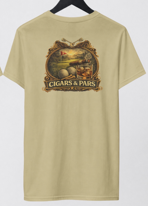 A sand color short-sleeve t-shirt hanging on a black hanger, featuring a large vintage-style graphic on the back of the shirt with the text 'CIGARS & PARS' and illustrations of a golf course, cigar, golf balls and tees, and a whiskey glass.