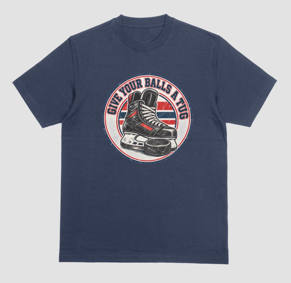 A navy blue t-shirt with a round vintage crest reading 'Give Your Balls a Tug' around a hockey skate and puck in red, white, and blue.