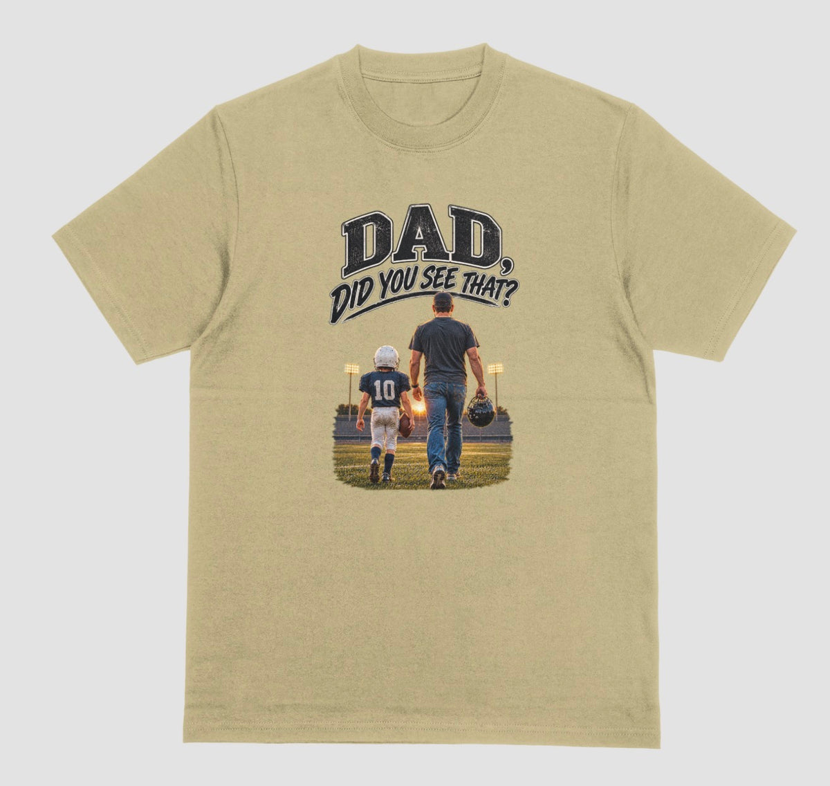 A sand color crewneck t-shirt featuring a graphic print on the front. The graphic shows a father and son walking on a football field at night, with the text 'DAD DID YOU SEE THAT?' above them.
