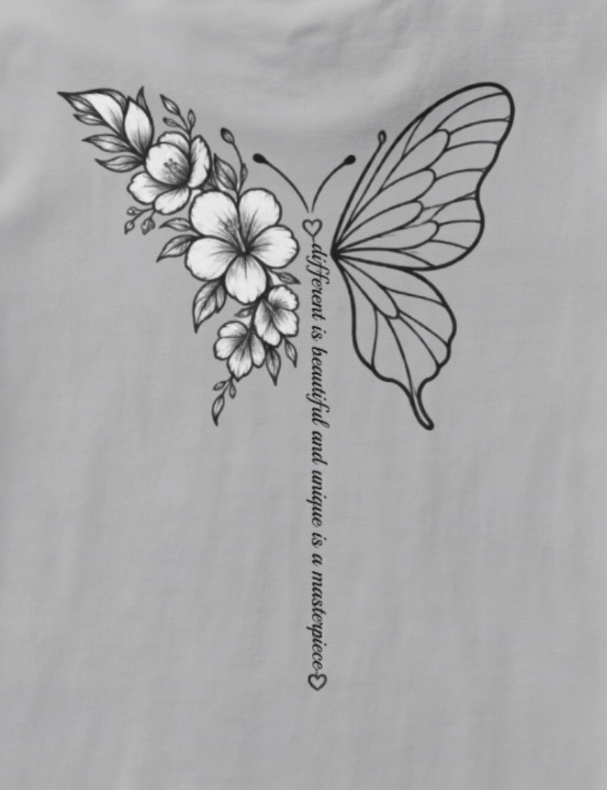 Close up of the back of the shirt, Butterfly half made out of flowers half normally illustrated the body is made out of a line of text that reads: "different is beautiful and unique is a masterpiece"