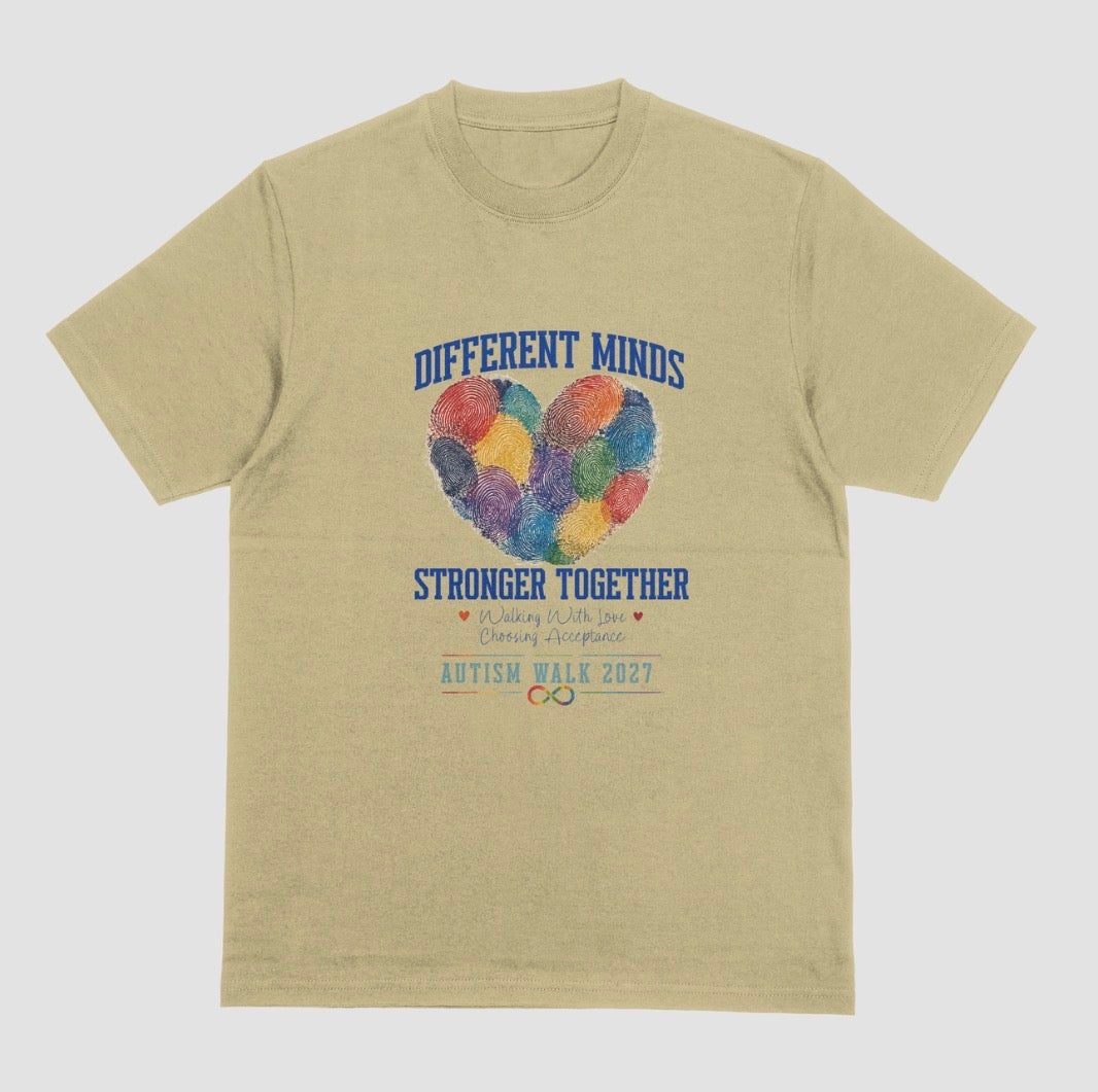 A sand crewneck t-shirt featuring a graphic design for the 'Autism Walk 2027'. The design includes the text 'DIFFERENT MINDS STRONGER TOGETHER' in blue, a heart made of colorful fingerprint patterns in the center, and the 'Autism Walk 2027' logo at the bottom.