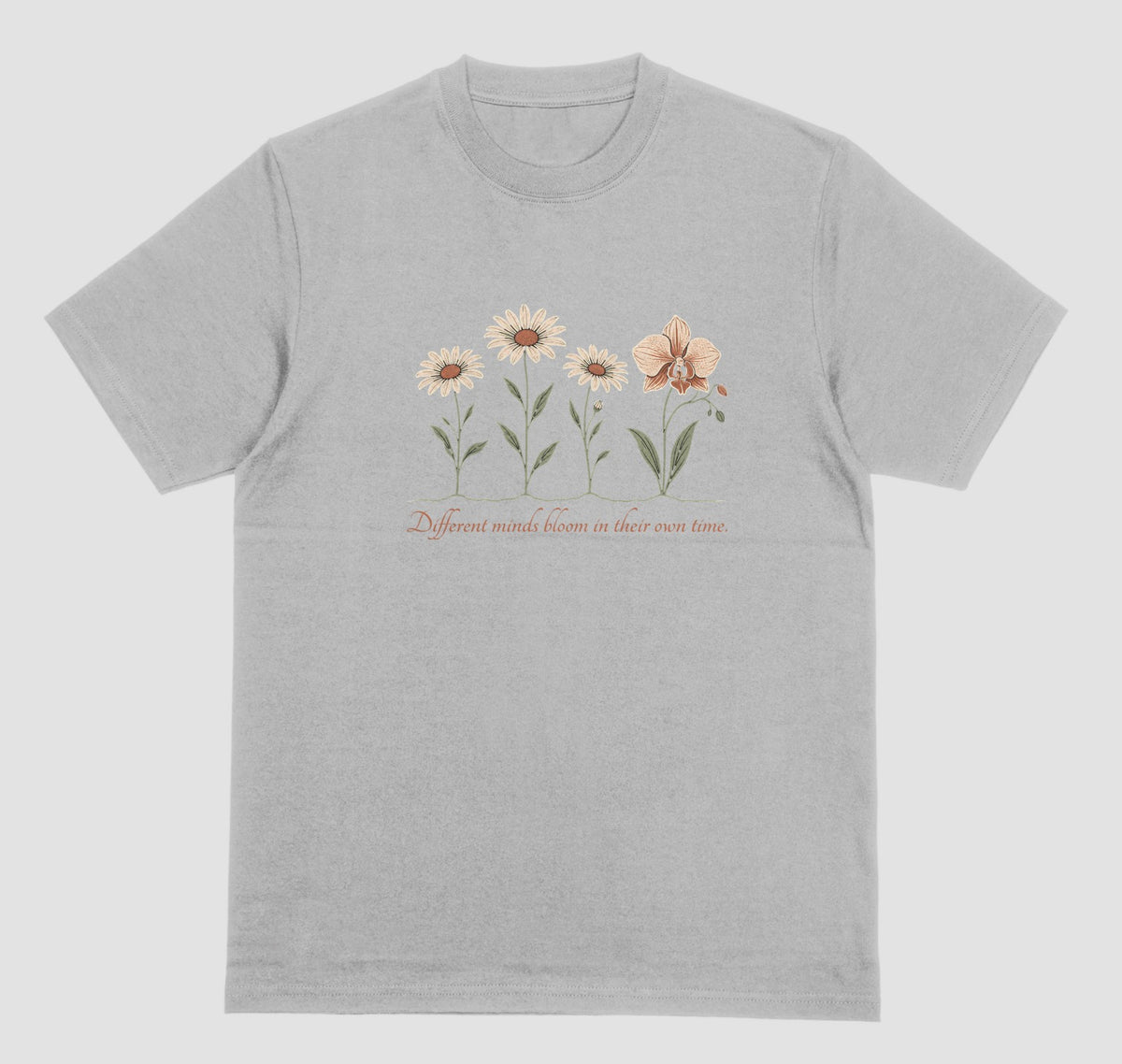 A grey t-shirt with an illustration of three daisies and an orchid and the script text ‘Different minds bloom in their own time.’