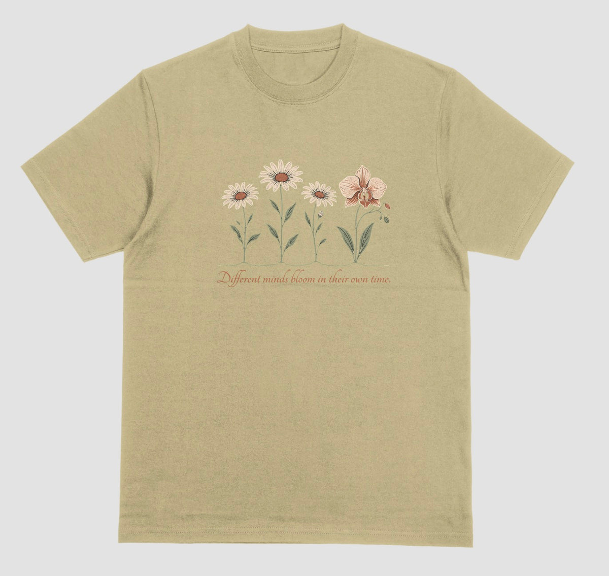 A sand color t-shirt with an illustration of three daisies and an orchid and the script text ‘Different minds bloom in their own time.’