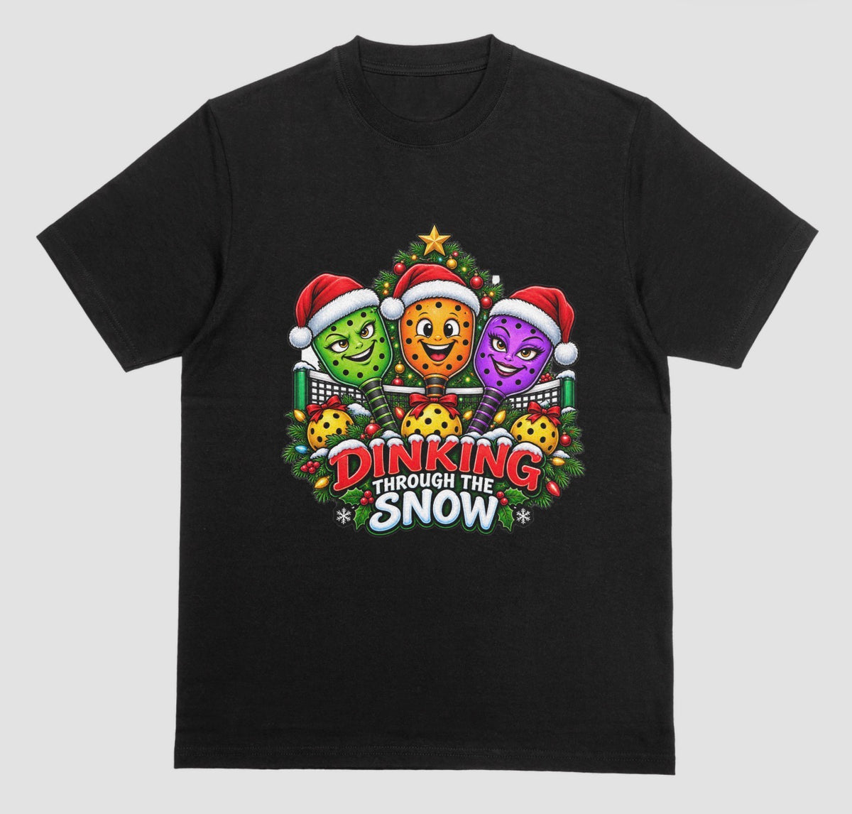 A black t-shirt with “Dinking Through the Snow” Christmas design featuring pickleball paddles in Santa hats