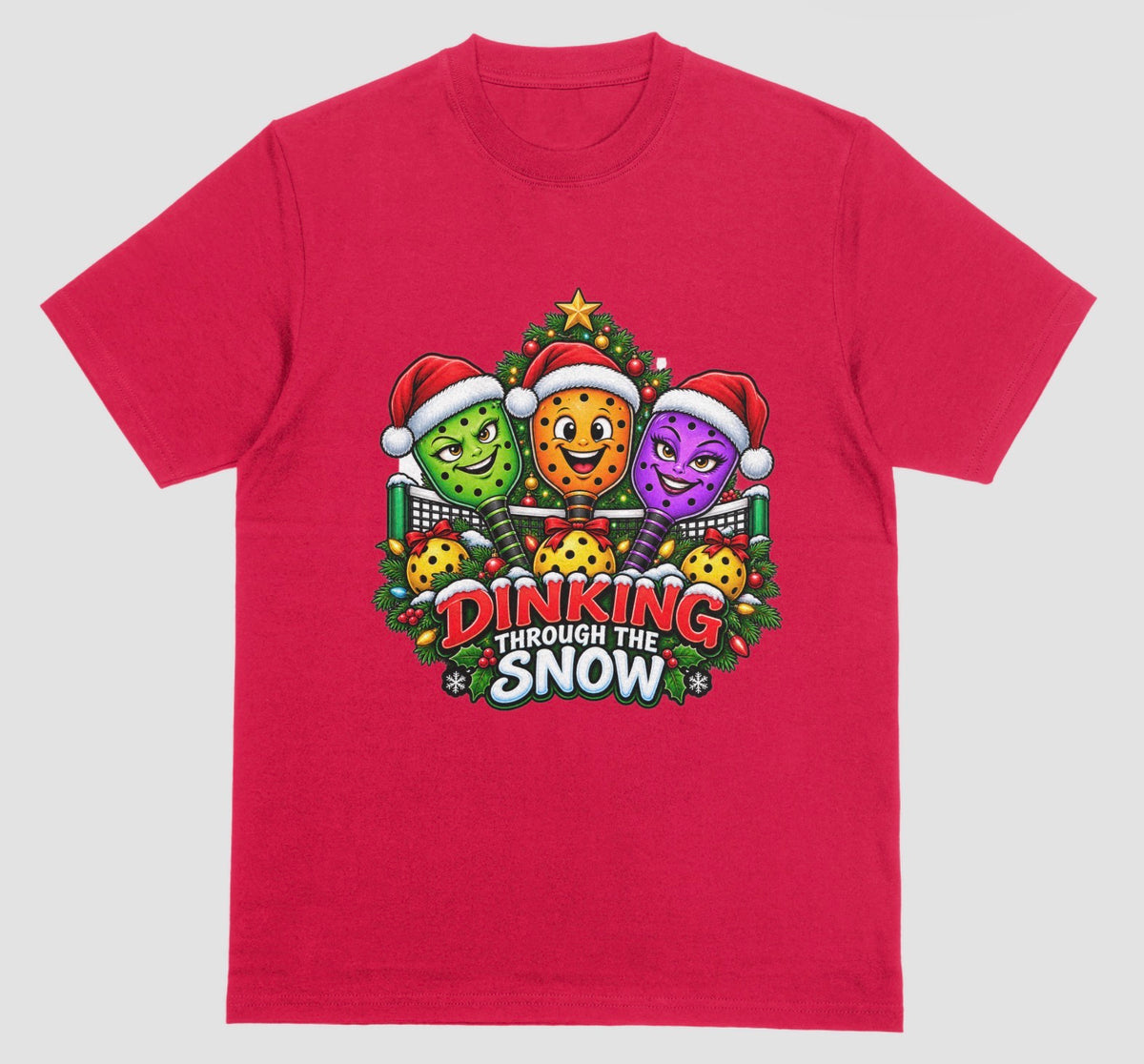 A red t-shirt with “Dinking Through the Snow” Christmas design featuring pickleball paddles in Santa hats