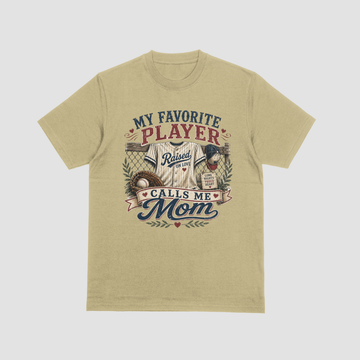 A sand color crewneck t-shirt featuring a baseball-themed graphic with a jersey, glove, and baseball, and the text “MY FAVORITE PLAYER CALLS ME MOM.”