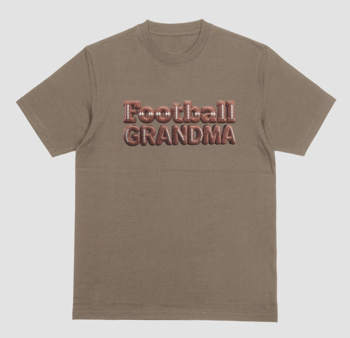 A brown savanna crewneck t-shirt featuring the words 'Football GRANDMA' printed across the chest in a 3D block font filled with a brown football leather texture and white laces.