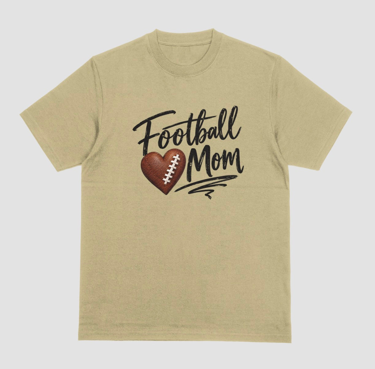 A sand color crewneck T-shirt featuring 'Football Mom' text in black script lettering, with a football-textured heart design between the words