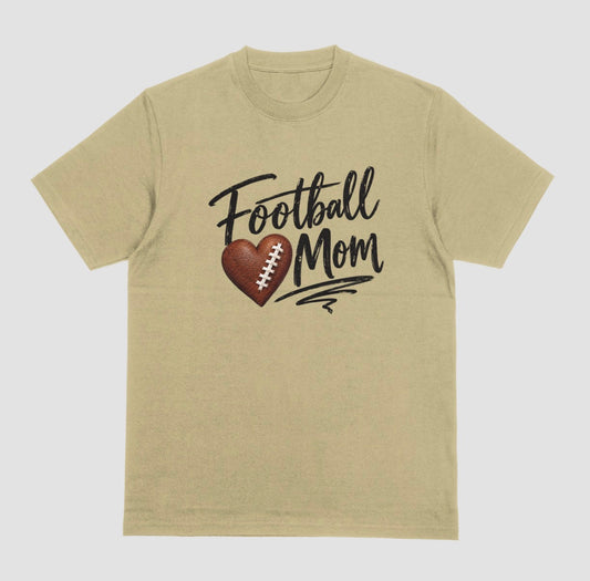 A sand color crewneck T-shirt featuring 'Football Mom' text in black script lettering, with a football-textured heart design between the words