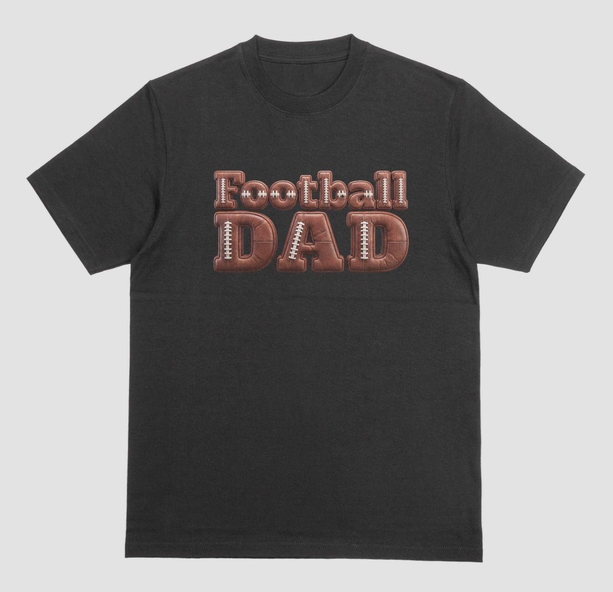 A black crewneck t-shirt featuring a graphic on the chest that reads 'Football DAD' in a 3D block font filled with a brown football leather texture and white laces.