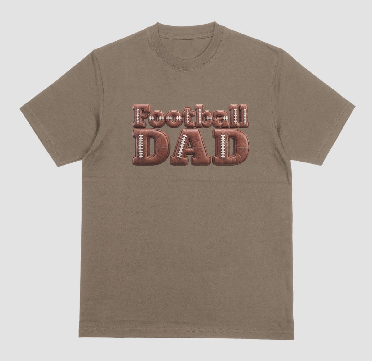 A brown savanna crewneck t-shirt featuring a graphic on the chest that reads 'Football DAD' in a 3D block font filled with a brown football leather texture and white laces.
