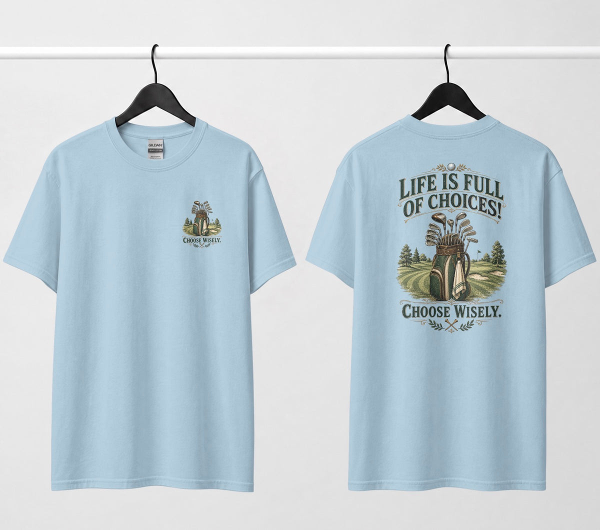 A light blue short-sleeve t-shirt shown from both the front and back, hanging on black hangers against a white wall. The design features a vintage-style illustration of a golf bag filled with clubs on a golf course, framed by the text 'LIFE IS FULL OF CHOICES! CHOOSE Wisely.