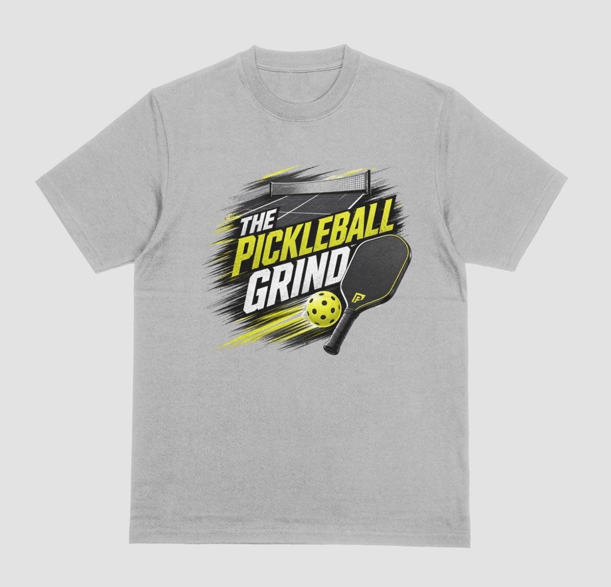 A light gray short-sleeve t-shirt with a 'The Pickleball Grind' graphic on the chest, featuring a yellow pickleball, black paddle, and yellow/black text over a gray brushstroke design, shown on a light gray background.