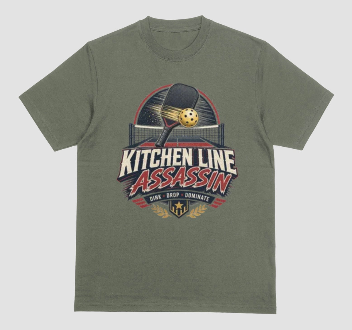 An military green crewneck t-shirt featuring a graphic print on the front with a pickleball paddle and ball above the text 'KITCHEN LINE ASSASSIN' and 'DINK - DROP - DOMINATE'.