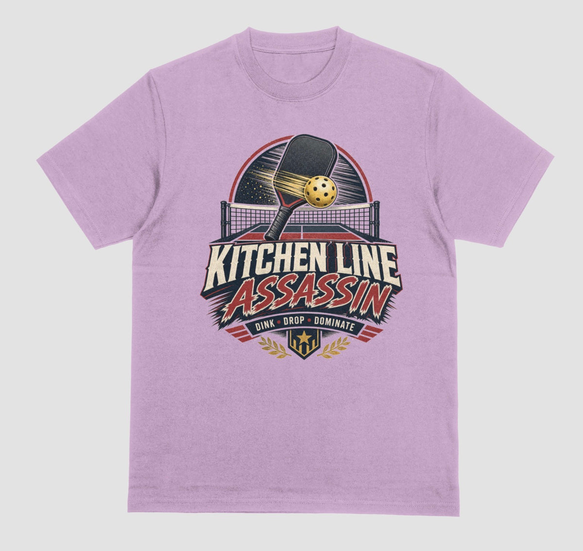 A lilac crewneck t-shirt featuring a graphic print on the front with a pickleball paddle and ball above the text 'KITCHEN LINE ASSASSIN' and 'DINK - DROP - DOMINATE'.