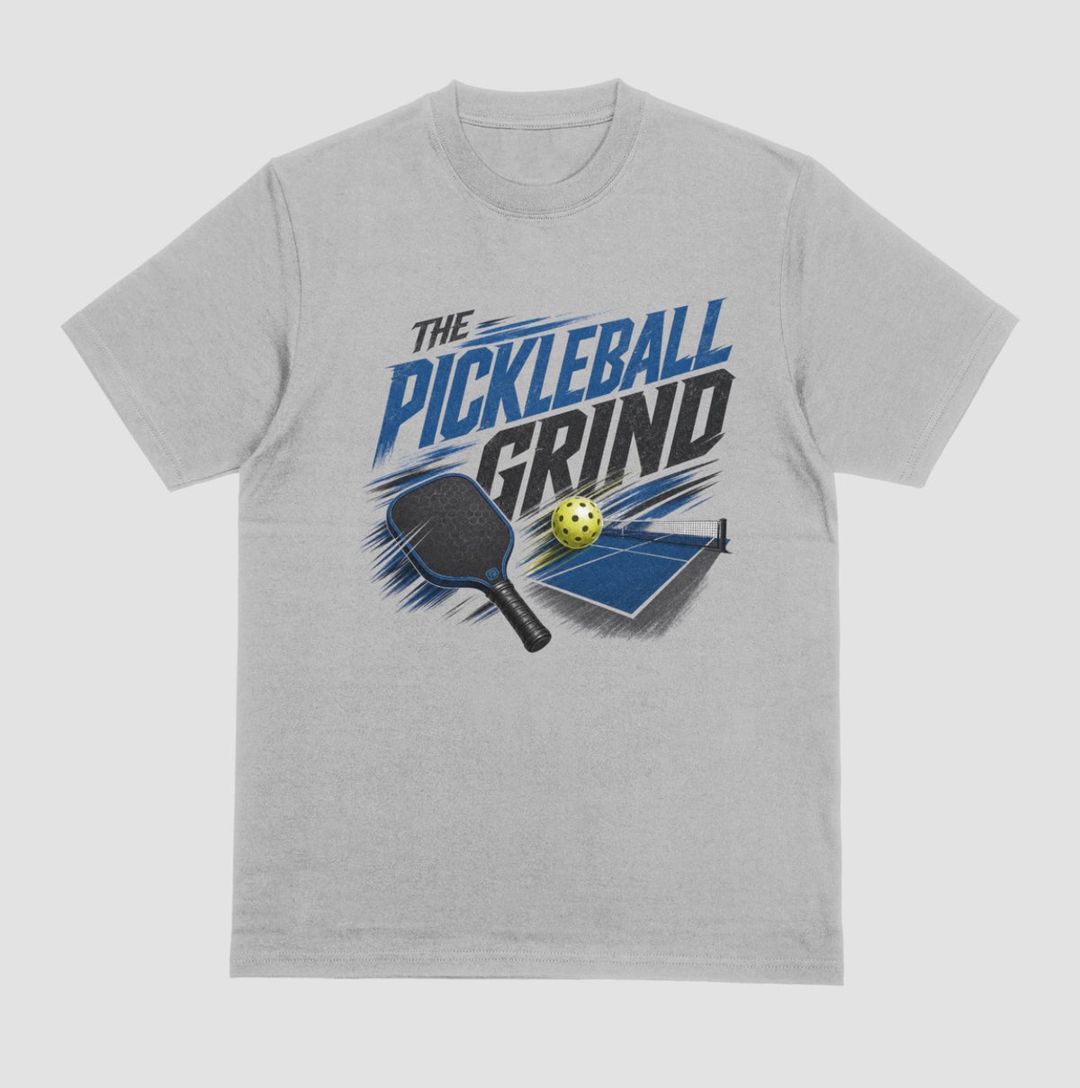 A gray short-sleeve t-shirt with a graphic on the front that reads 'THE PICKLEBALL GRIND' in blue and black, accompanied by illustrations of a pickleball paddle, ball, and table.