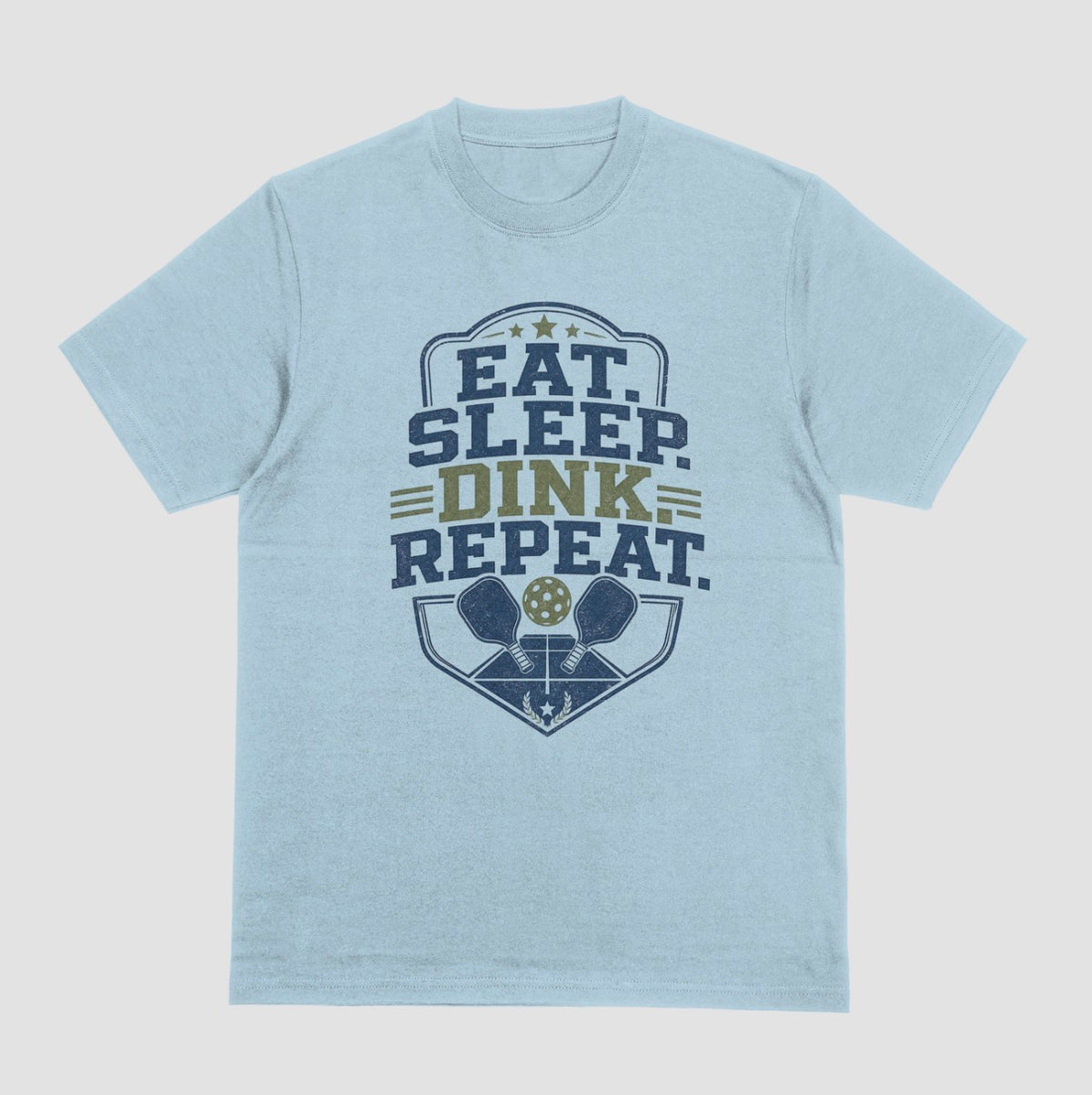A light blue heather crewneck t-shirt featuring a distressed graphic on the front with the text 'EAT. SLEEP. DINK. REPEAT.'