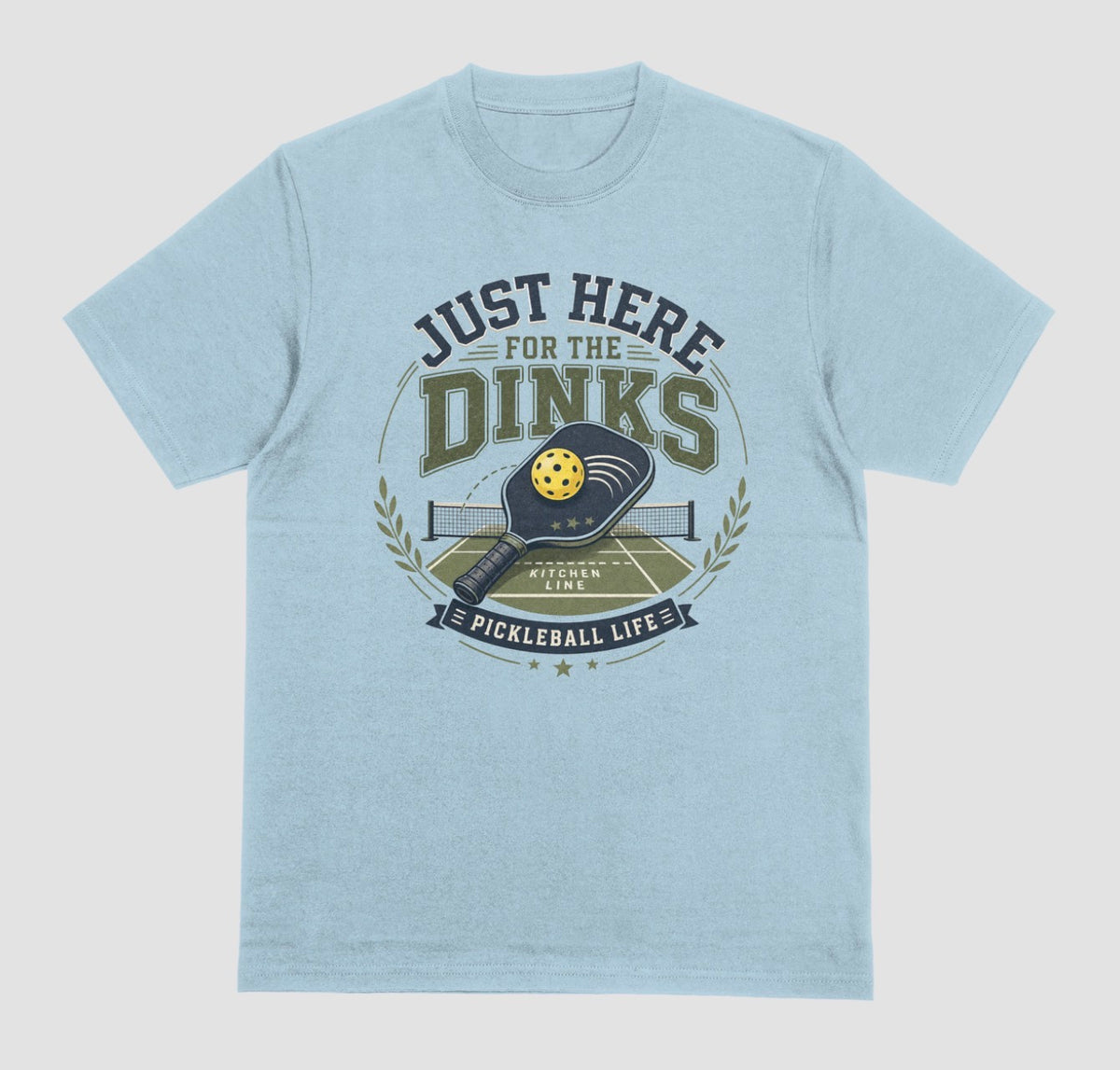 A light blue short-sleeve t-shirt with a vintage-style graphic on the chest. The graphic features the text 'JUST HERE FOR THE DINKS' and 'PICKLEBALL LIFE' surrounding an illustration of a pickleball paddle, ball, and court.