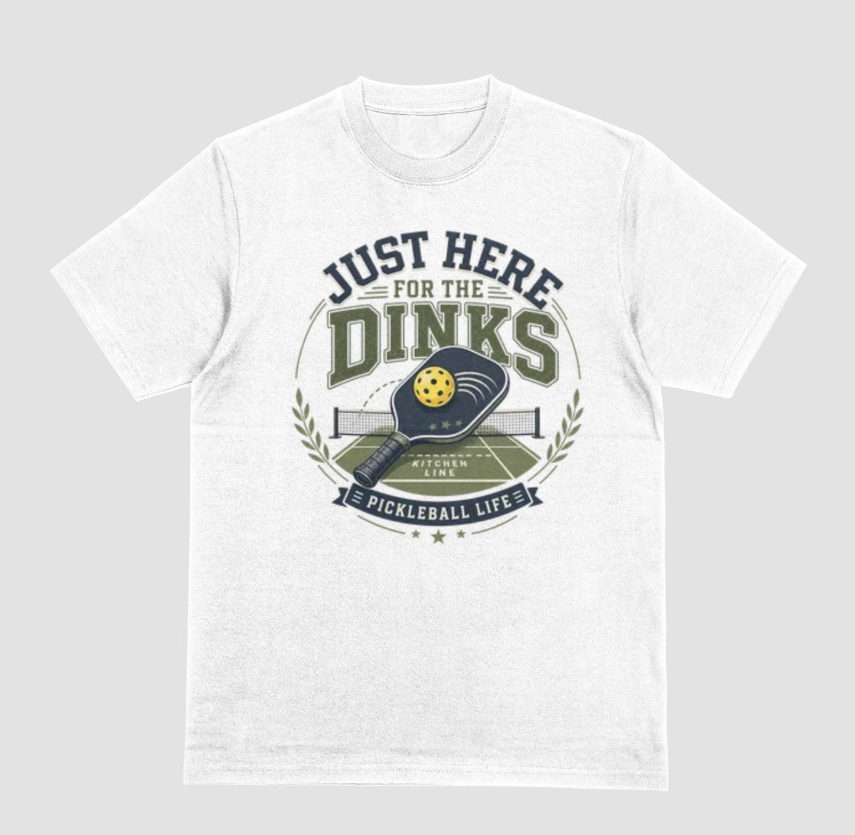 A white t-shirt with a vintage-style graphic on the chest that reads 'JUST HERE FOR THE DINKS' and 'PICKLEBALL LIFE!' around an illustration of a paddle, ball, and court.