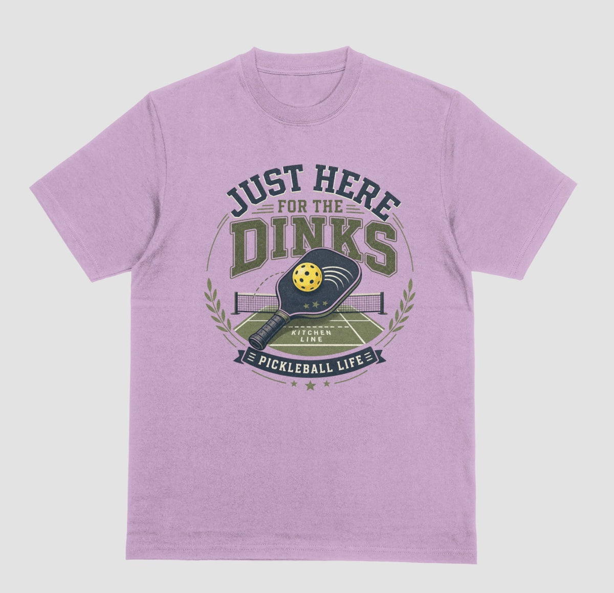A lilac t-shirt with a vintage-style graphic on the chest that reads 'JUST HERE FOR THE DINKS' and 'PICKLEBALL LIFE!' around an illustration of a paddle, ball, and court.