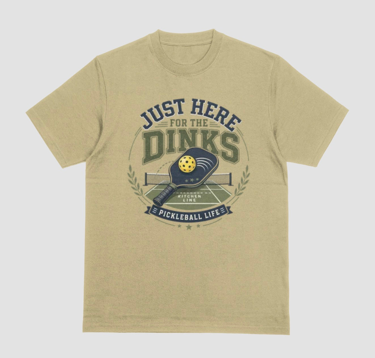 A sand color t-shirt with a vintage-style graphic on the chest that reads 'JUST HERE FOR THE DINKS' and 'PICKLEBALL LIFE!' around an illustration of a paddle, ball, and court.