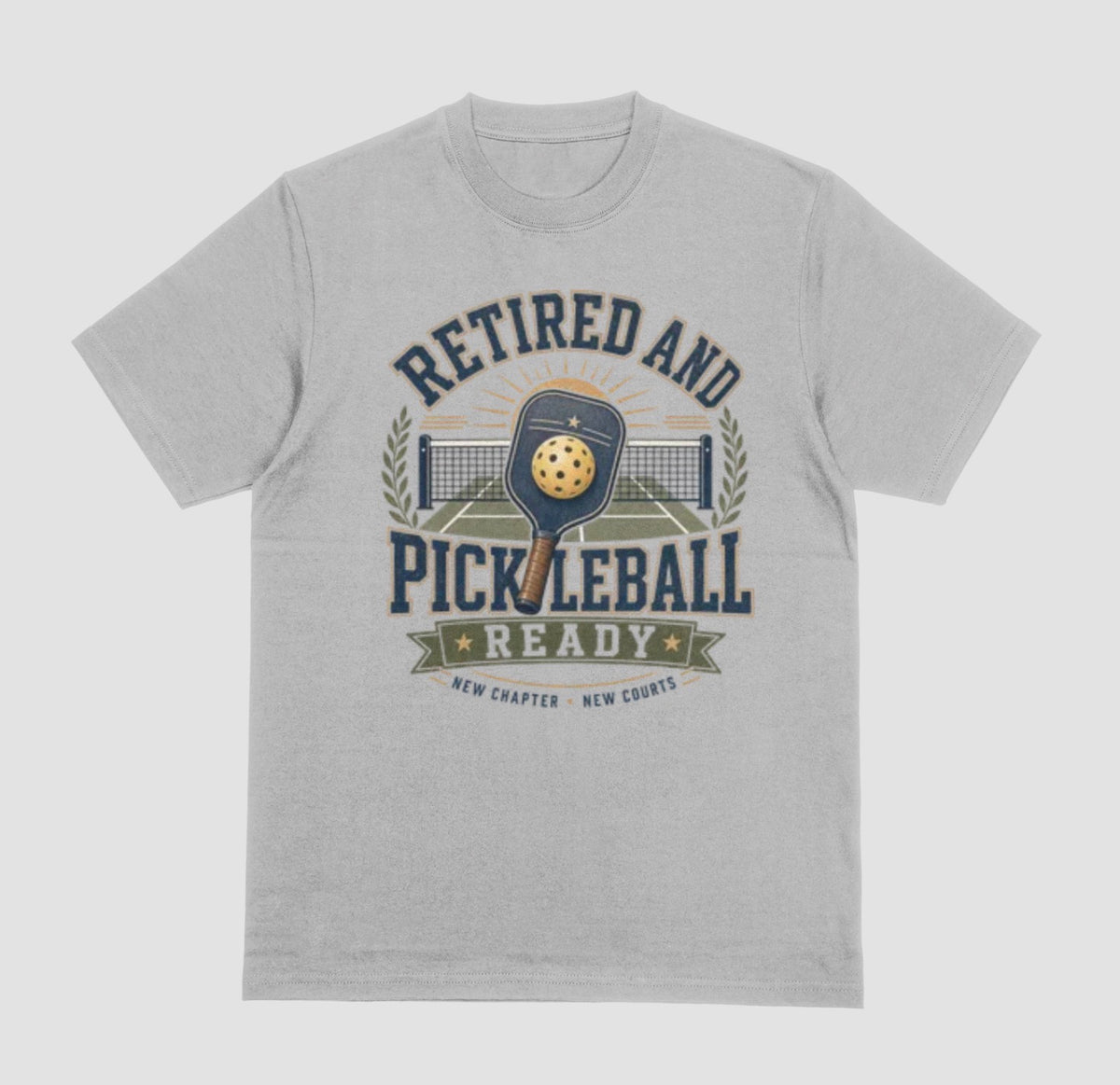 A gray crewneck t-shirt with the saying 'RETIRED AND PICKLEBALL READY' with a pickleball and paddle displayed with a vintage style.