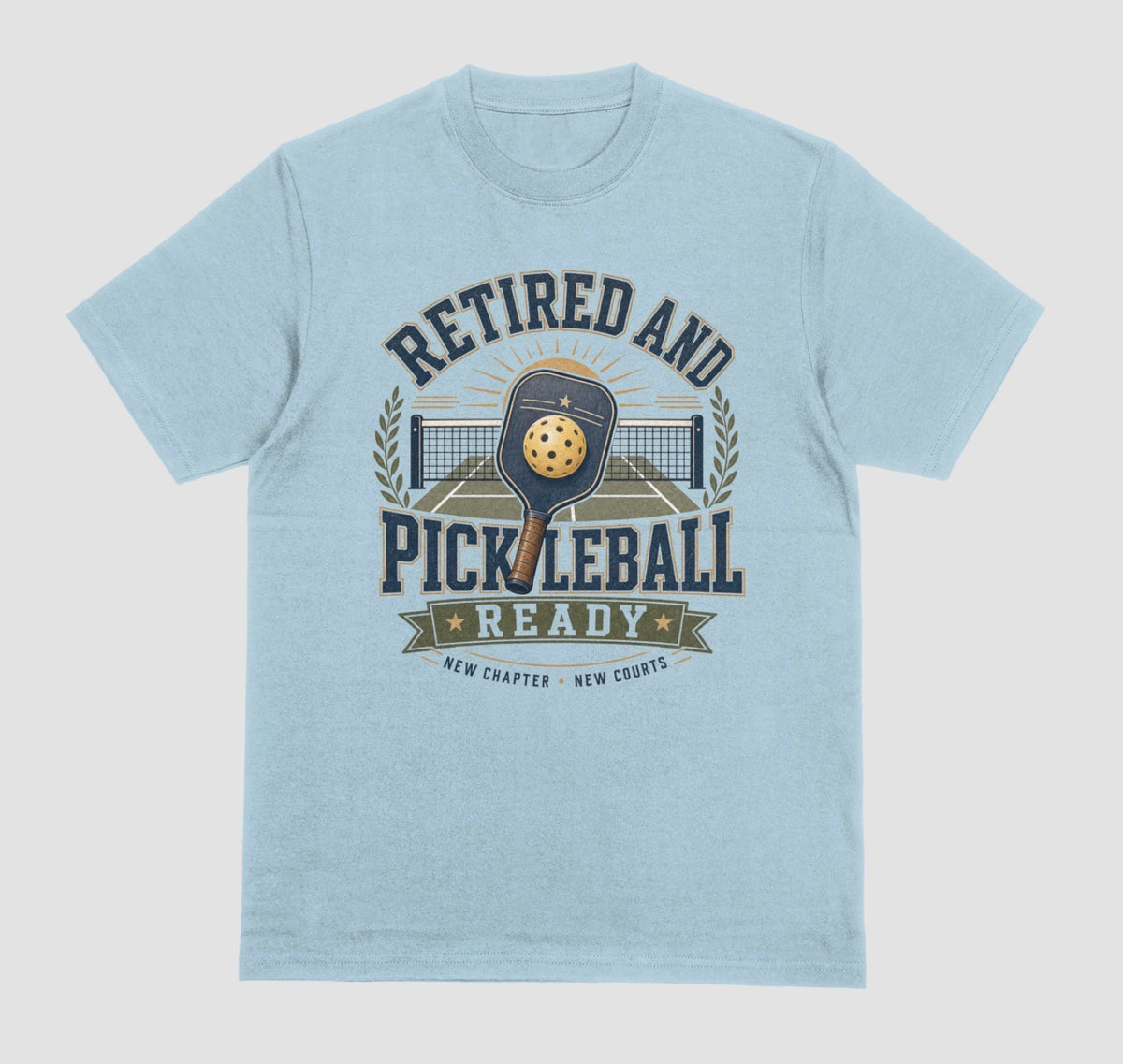 A light blue short-sleeve t-shirt with a vintage-style graphic on the front that reads 'RETIRED AND PICKLEBALL READY' around an illustration of a paddle and ball.