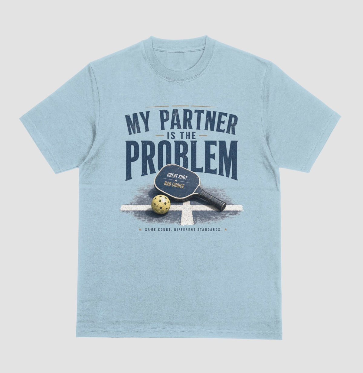 A light blue short-sleeve t-shirt with a vintage-style graphic on the front. The graphic features the text 'MY PARTNER IS THE PROBLEM' in dark blue, along with a paddle, ball, and net illustration.