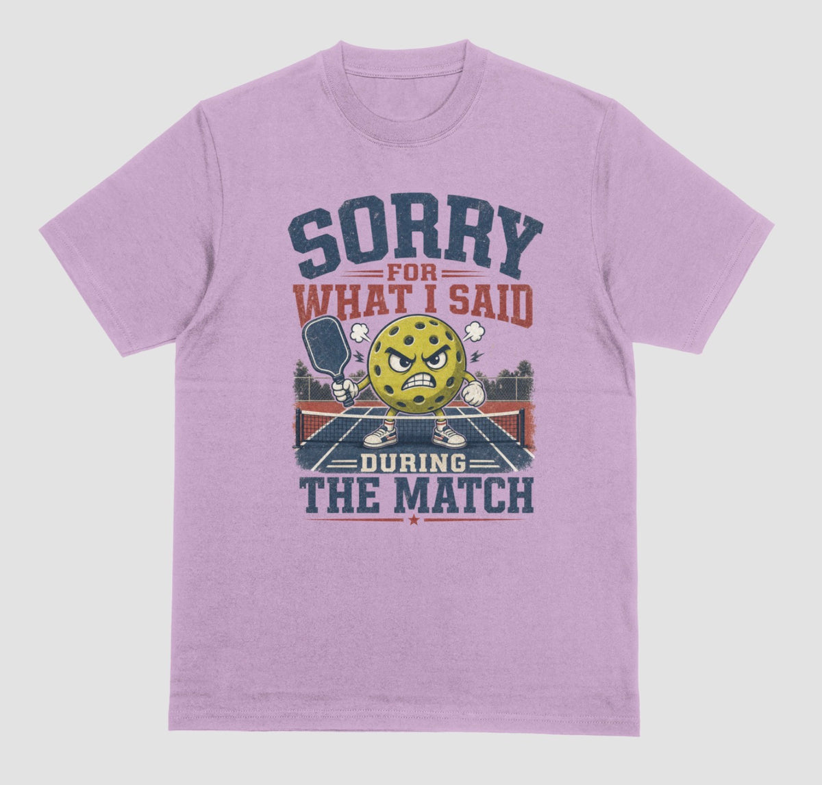 A lilac short-sleeve t-shirt with a distressed graphic on the front. The graphic features a yellow cartoon pickleball with an angry face, a pickleball paddle, and the text 'SORRY FOR WHAT I SAID DURING THE MATCH' in navy blue and red lettering, set against a solid light gray background.
