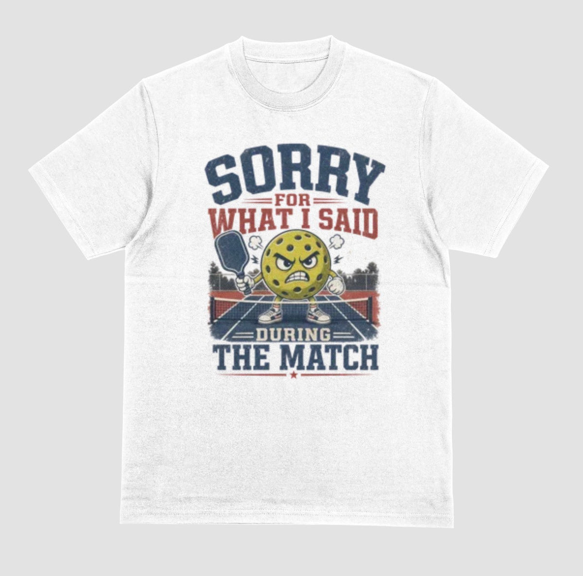 A white short-sleeve t-shirt with a distressed graphic on the front. The graphic features a yellow cartoon pickleball with an angry face, a pickleball paddle, and the text 'SORRY FOR WHAT I SAID DURING THE MATCH' in navy blue and red lettering, set against a solid light gray background.