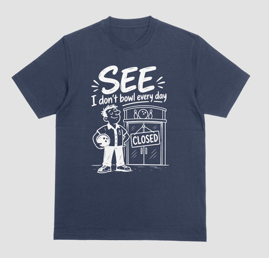 A navy blue short-sleeve t-shirt with a white graphic print on the front. The graphic features a cartoon bowling player holding a bowling ball next to a bowling alley door with a 'CLOSED' sign, with the text 'SEE I don't bowl every day' above.