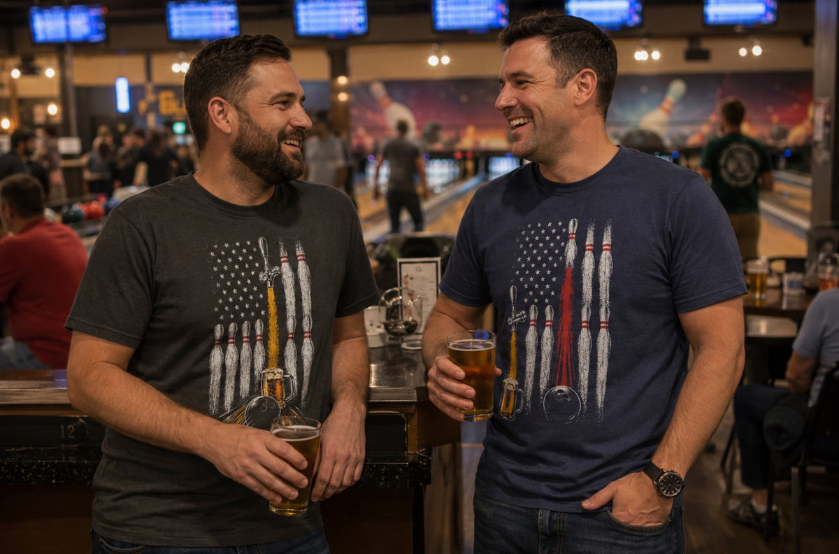 Two men laughing and holding pint glasses in a bowling alley, wearing different Beer, Bowling and American Flag t-shirts featuring an American flag made of bowling pins and balls.