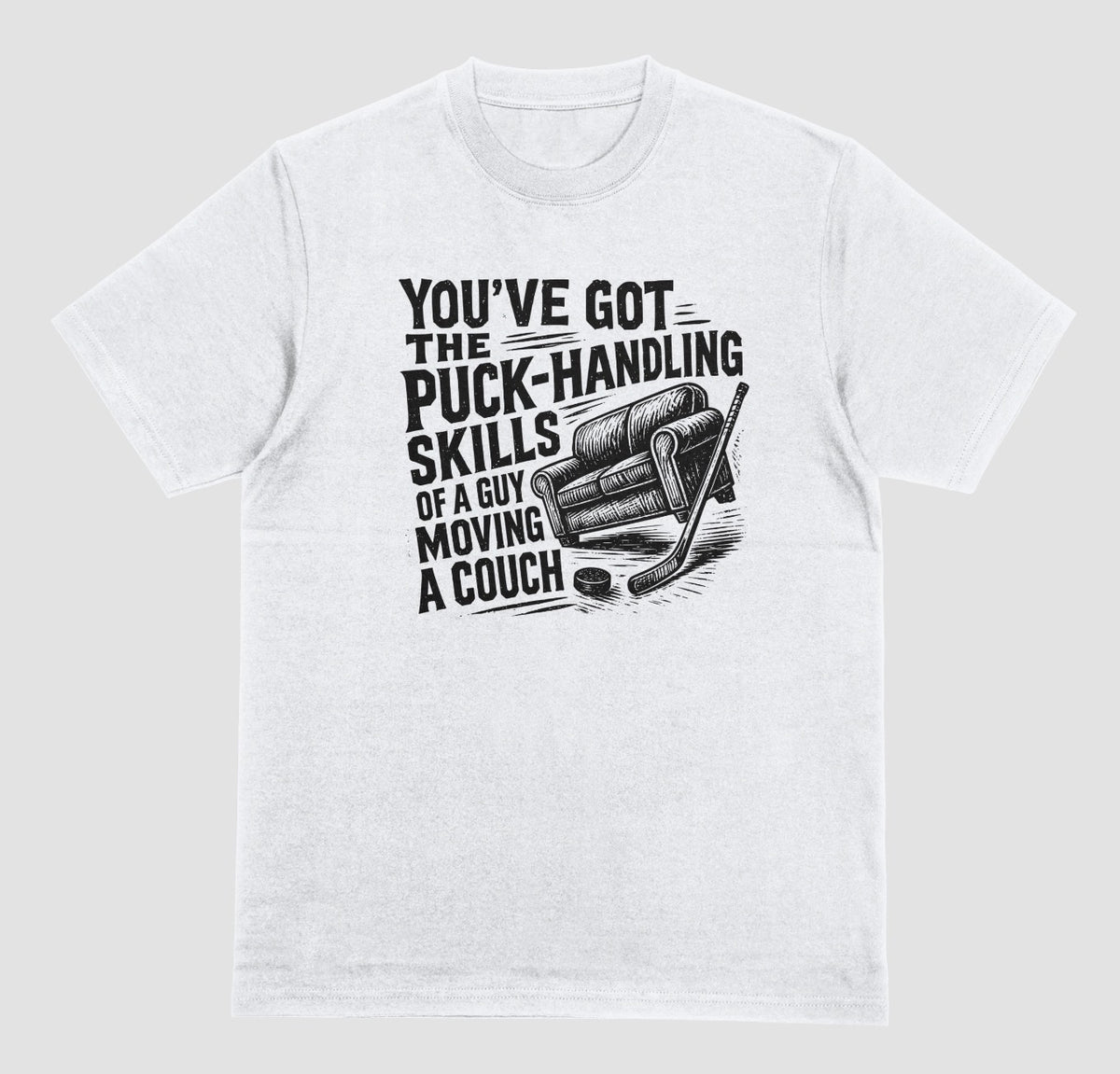 A white hockey humor t-shirt with black graphic of a couch, hockey stick, and puck, reading “You’ve got the puck-handling skills of a guy moving a couch”