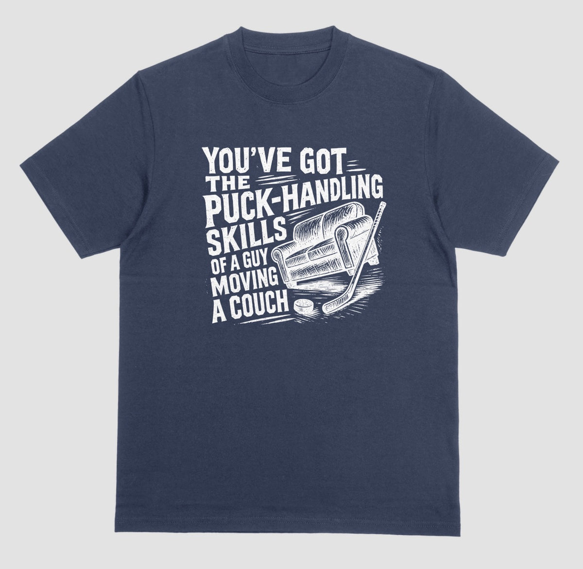 A navy blue hockey humor t-shirt with white graphic of a couch, hockey stick, and puck, reading “You’ve got the puck-handling skills of a guy moving a couch”