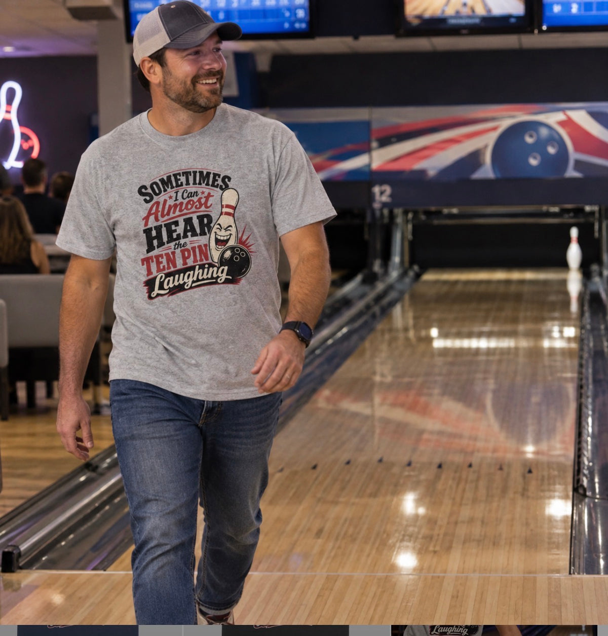Smiling man in a trucker hat and grey "Sometimes I Can Almost Hear the Ten Pin Laughing" bowling t-shirt walking away from the lane after leaving a single pin standing