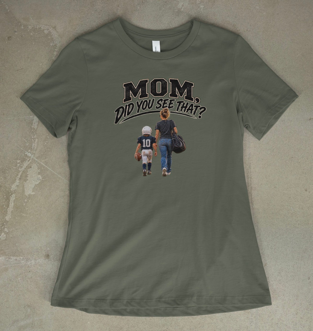 A military green short-sleeve t-shirt with a graphic print on the front that reads 'MOM DID YOU SEE THAT?' above an illustration of a mother and child walking away, laid flat on a textured concrete surface.