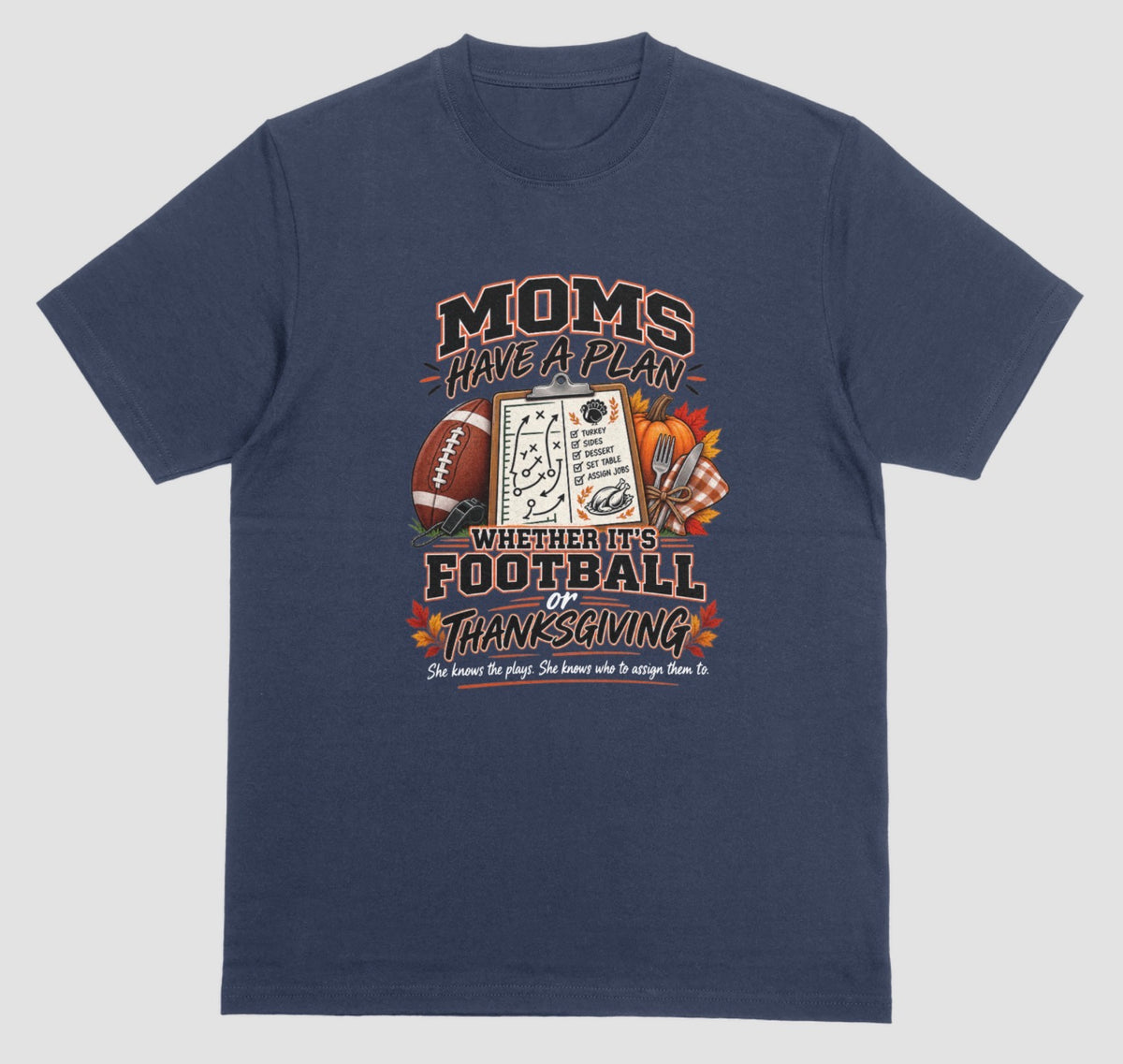 a navy blue t-shirt featuring 'Moms Have a Plan, Whether It's Football or Thanksgiving' quote with football, clipboard playbook, pumpkin, and turkey dinner graphics"