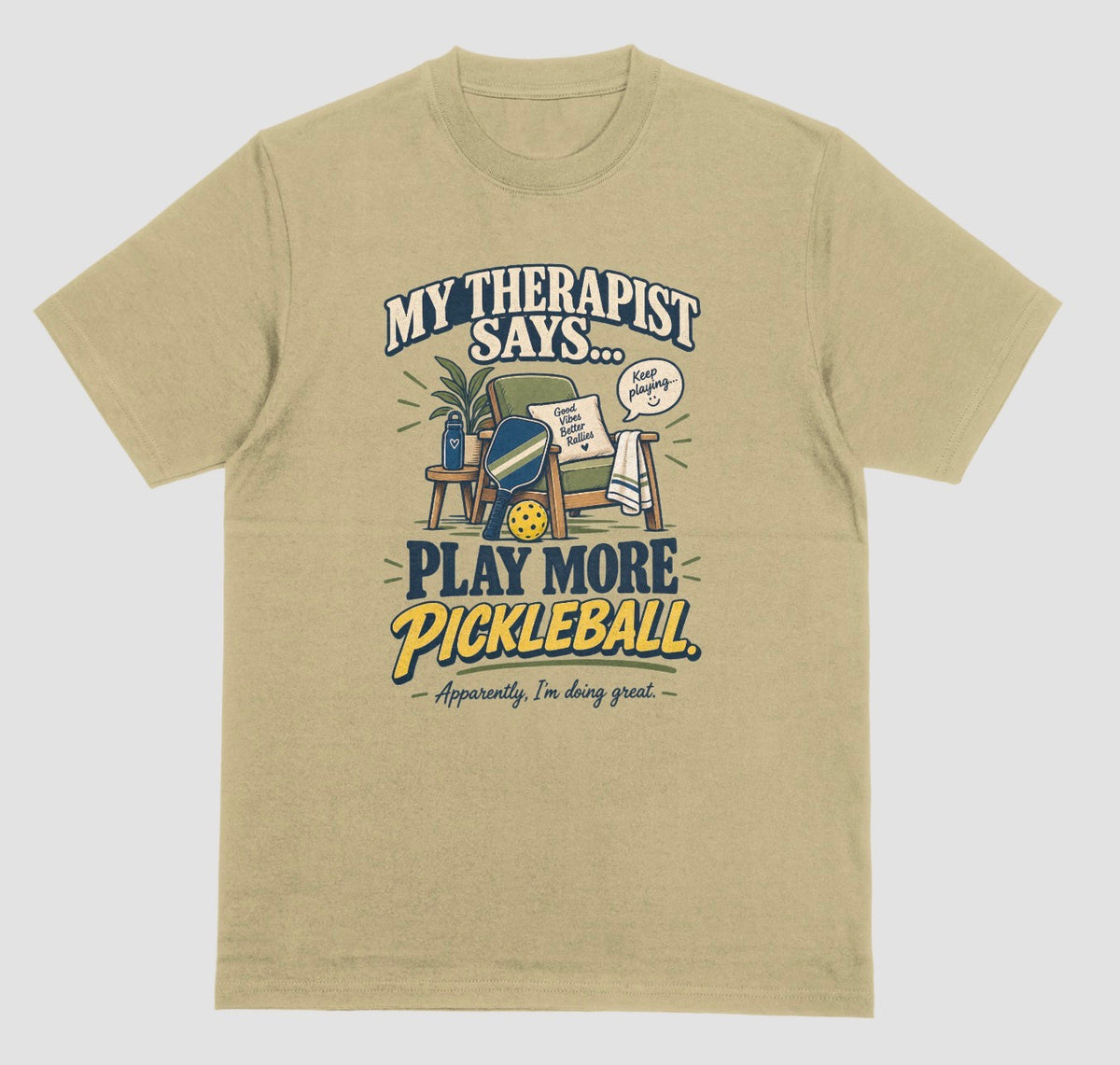 A sand color Funny pickleball shirt with an armchair and paddle design that says My Therapist Says Play More Pickleball