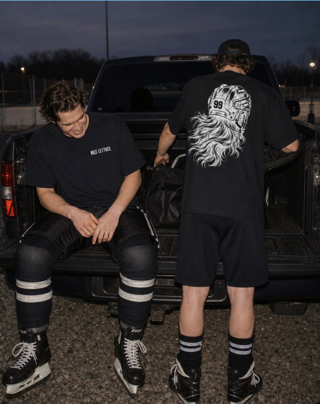 Two hockey players at a pickup tailgate in black tees: 'Nice Lettuce' on the chest, number 99 helmet and flowing hair on back.