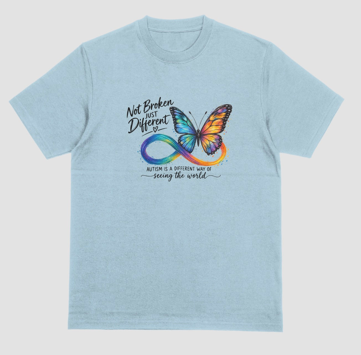 A light blue t-shirt with a colorful butterfly and rainbow infinity symbol, with the text ‘Not Broken, Just Different’ and ‘Autism is a different way of seeing the world.’