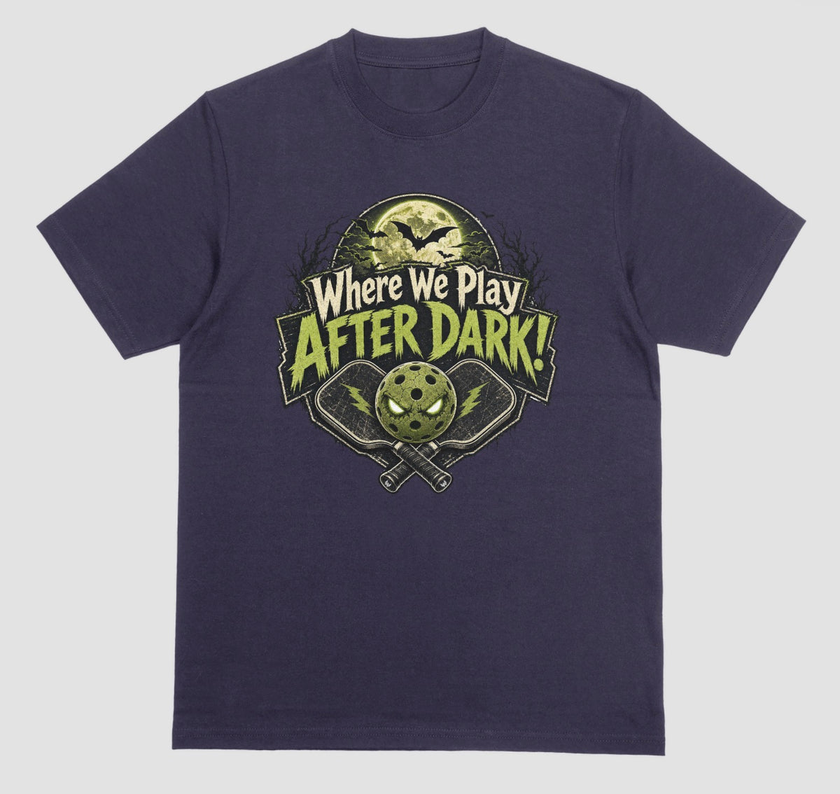 A blackberry t-shirt with a spooky pickleball graphic reading 'Where We Play After Dark!' showing crossed paddles and a glowing-eyed pickleball under a full moon with bats.